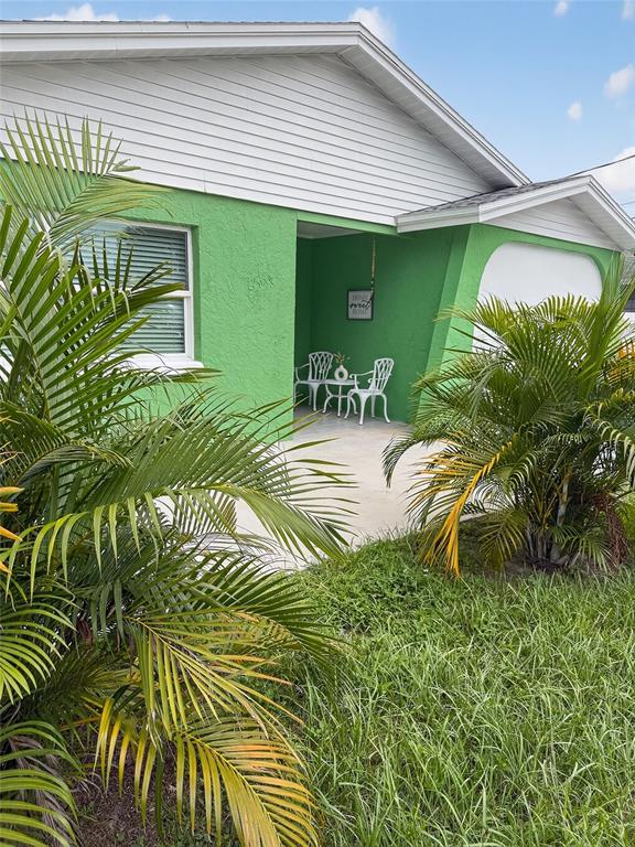 A green house exterior features a covered entryway with white chairs and palm trees — 2311 W KENTUCKY AVENUE, TAMPA, FL