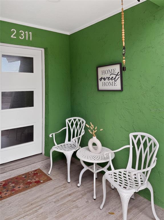 A white patio set sits on a porch with green textured walls and a door — 2311 W KENTUCKY AVENUE, TAMPA, FL