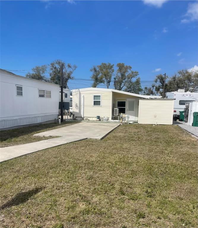 A single-story mobile home with a concrete driveway and an attached shed sits outdoors — 59 INDIANA STREET, PALMETTO, FL
