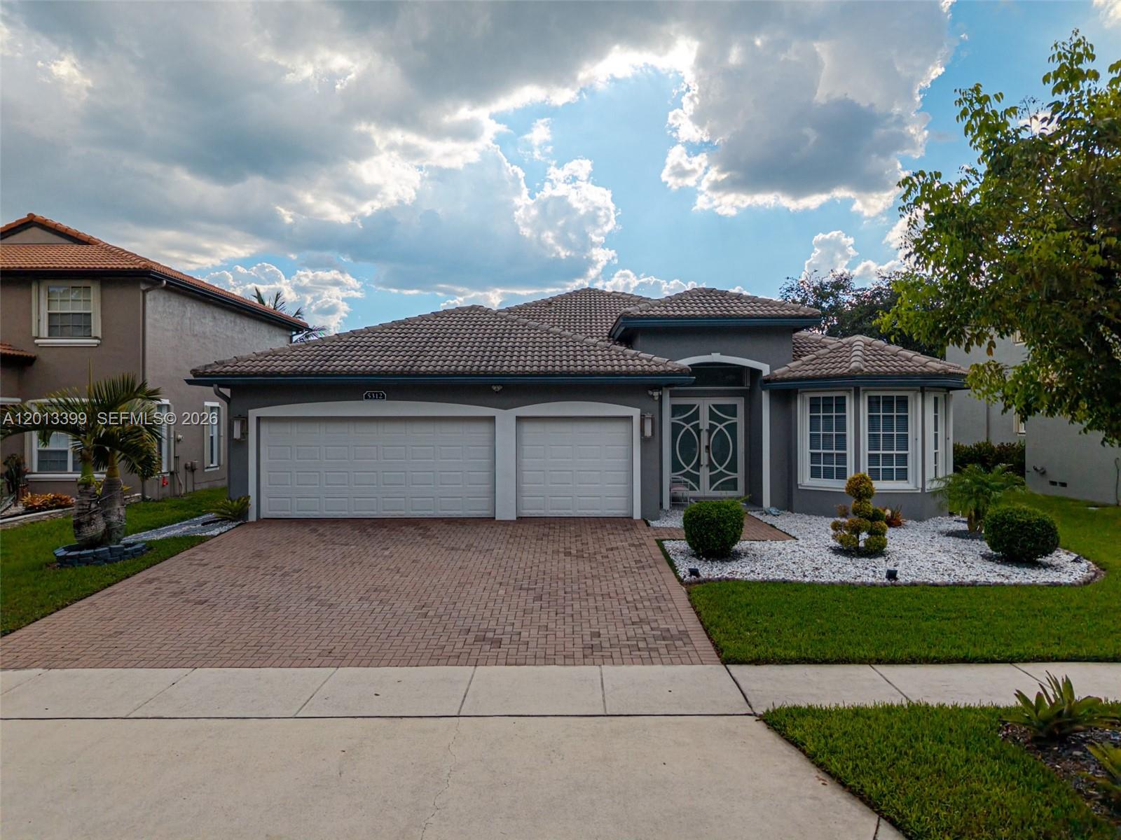 A gray single-story house with a tiled roof, two-car garage, and a brick paver driveway — 5312 SW 148th Ave, Miramar FL 33027, MIRAMAR, FL