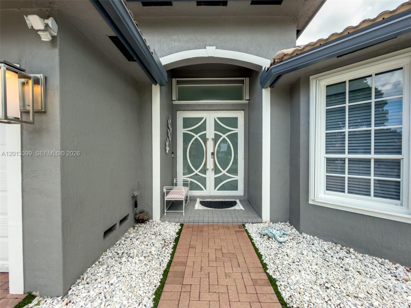 The exterior entrance features a brick walkway, white gravel, and double doors with circular patterns — 5312 SW 148th Ave, Miramar FL 33027, MIRAMAR, FL