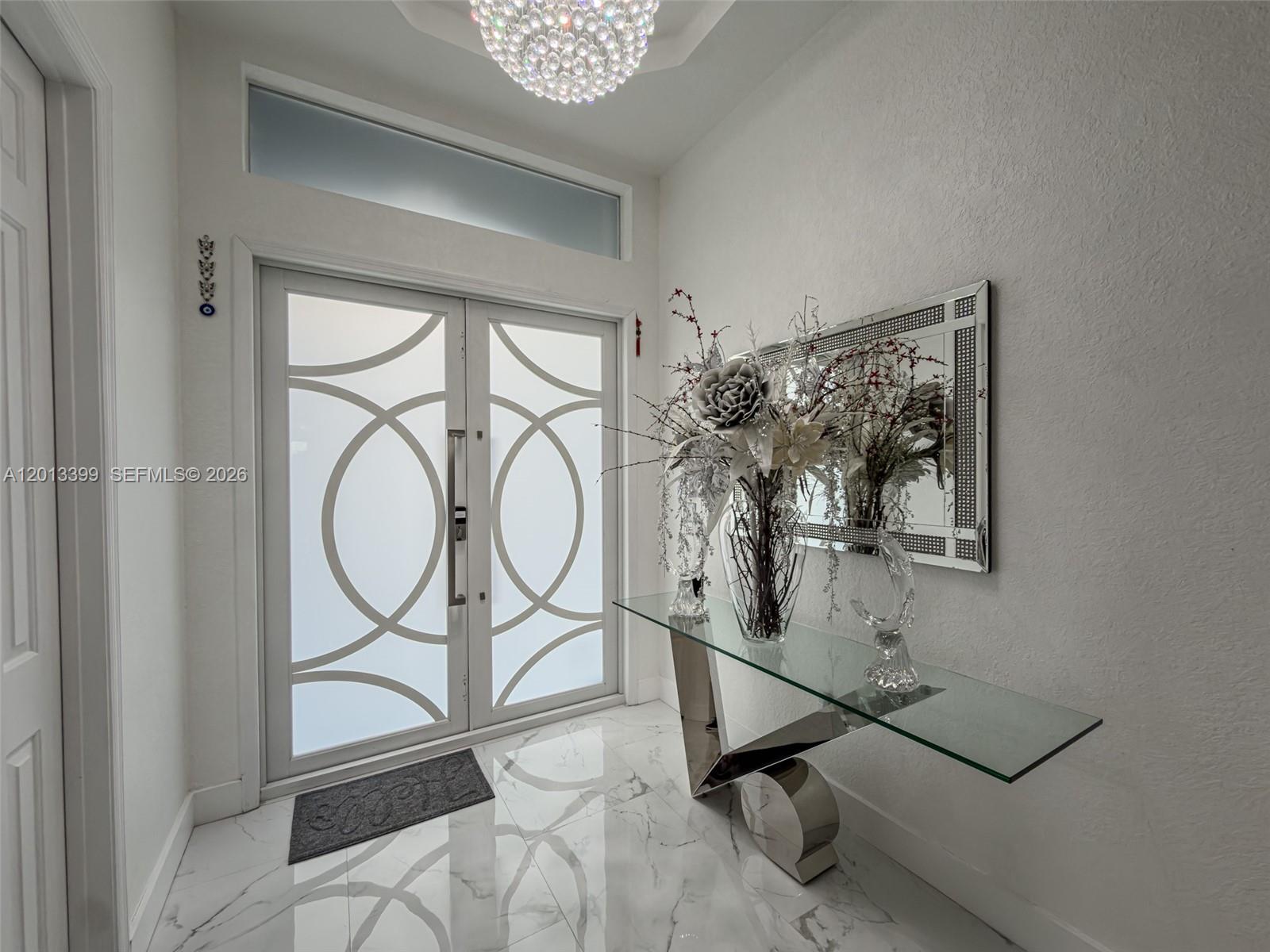 A bright entryway features a glass console table, a decorative mirror, and double frosted doors — 5312 SW 148th Ave, Miramar FL 33027, MIRAMAR, FL