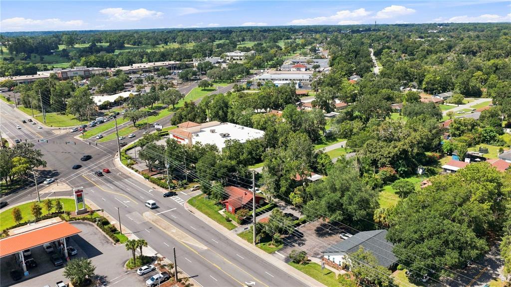 An aerial view shows a commercial intersection with a gas station, a pharmacy, and surrounding trees — 1112 NE 36TH AVENUE, OCALA, FL