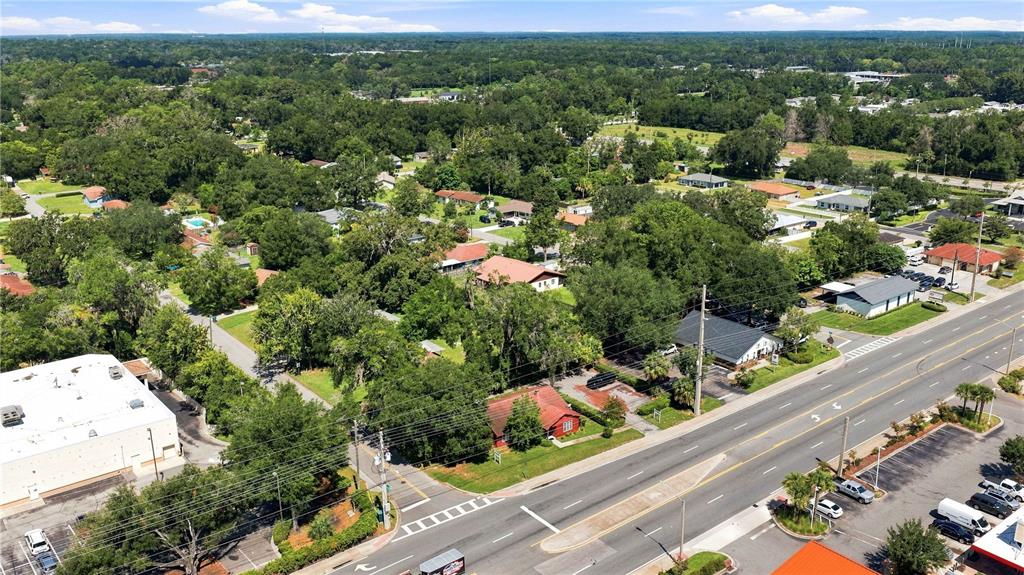 An aerial view shows a suburban neighborhood with houses, trees, and a multi-lane road — 1112 NE 36TH AVENUE, OCALA, FL
