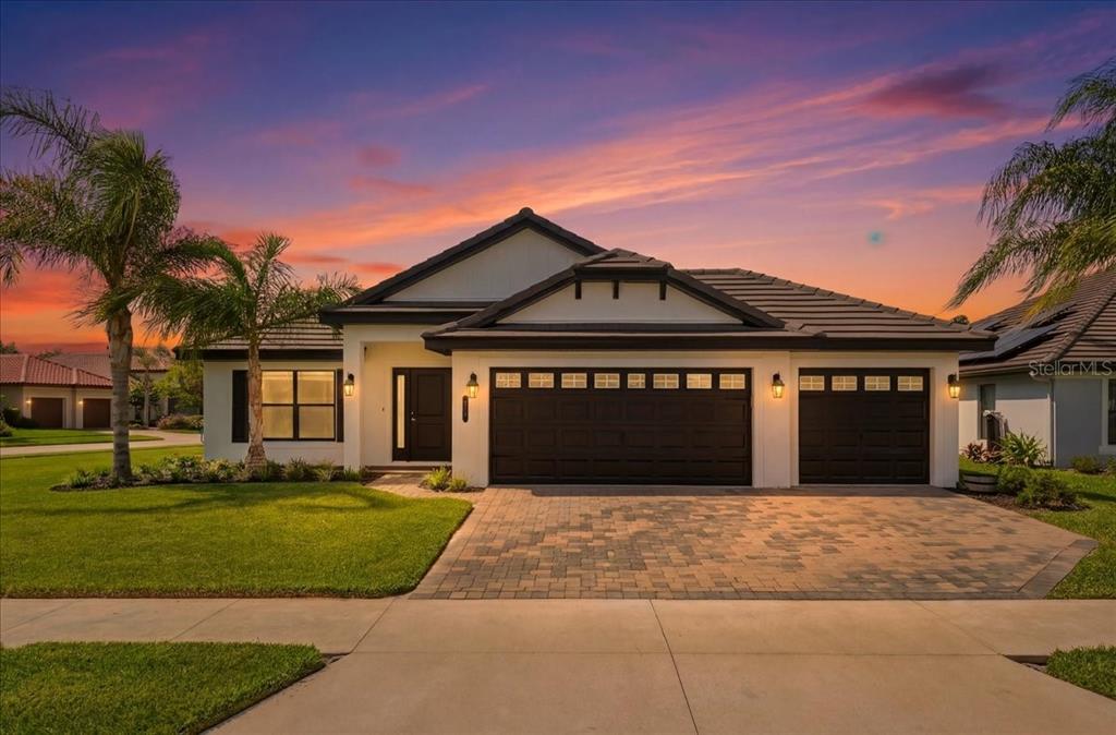 A single-story house with a three-car garage and a paved driveway at sunset — 477 LAKE VISTA DRIVE, AUBURNDALE, FL