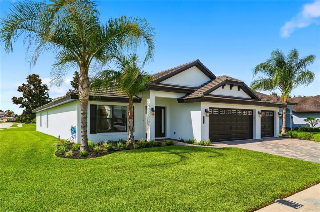 A single-story white house with a dark roof, a three-car garage, and two palm trees — 477 LAKE VISTA DRIVE, AUBURNDALE, FL