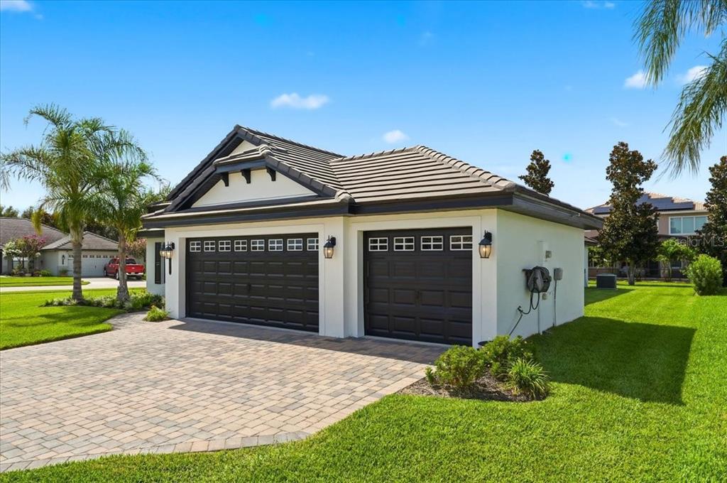 A detached three-car garage with black doors and a paved driveway on a grassy lot — 477 LAKE VISTA DRIVE, AUBURNDALE, FL