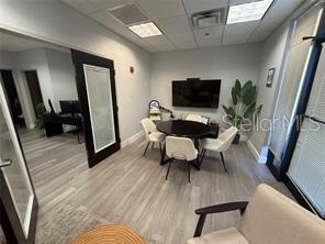 A modern office space features a round table, four chairs, a wall-mounted television, and wood-look flooring — 13574 VILLAGE PARK DRIVE UNIT GE, ORLANDO, FL