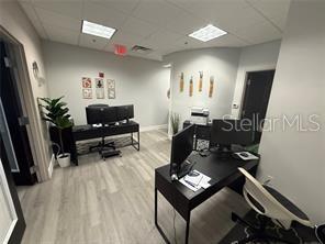 An office space features two black desks, light wood-look flooring, and neutral walls — 13574 VILLAGE PARK DRIVE UNIT GE, ORLANDO, FL