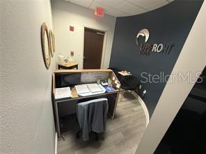 A small office space features a wooden desk, a chair, and a dark accent wall — 13574 VILLAGE PARK DRIVE UNIT GE, ORLANDO, FL