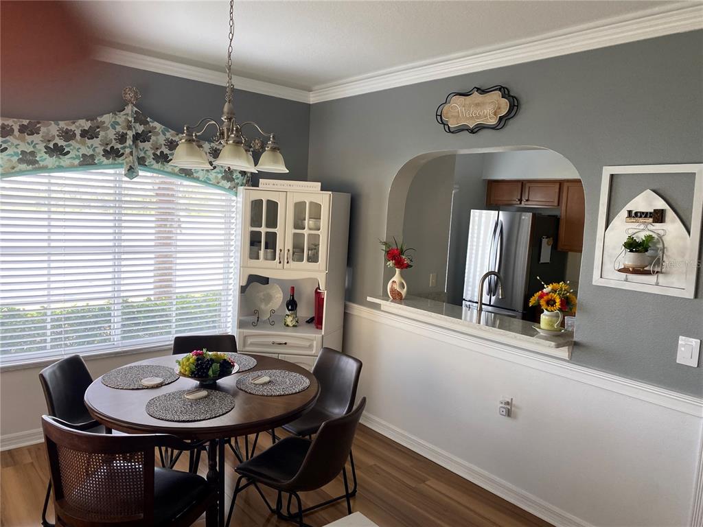 A dining area features a round wooden table, chairs, and an arched opening to the kitchen — 3603 45TH TERRACE W UNIT 101, BRADENTON, FL