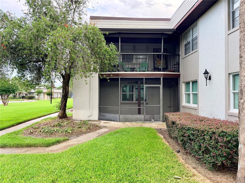 A two-story apartment building features a ground-level screened patio and an upper-level open balcony — 27 WINDTREE LANE UNIT 102, WINTER GARDEN, FL