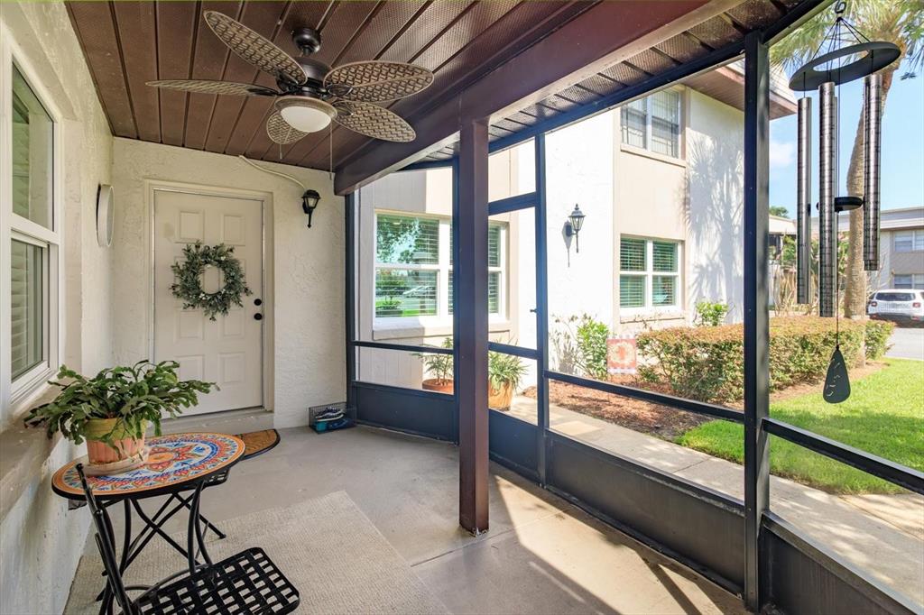 A screened-in porch features a ceiling fan, a small bistro table, and a white door — 27 WINDTREE LANE UNIT 102, WINTER GARDEN, FL