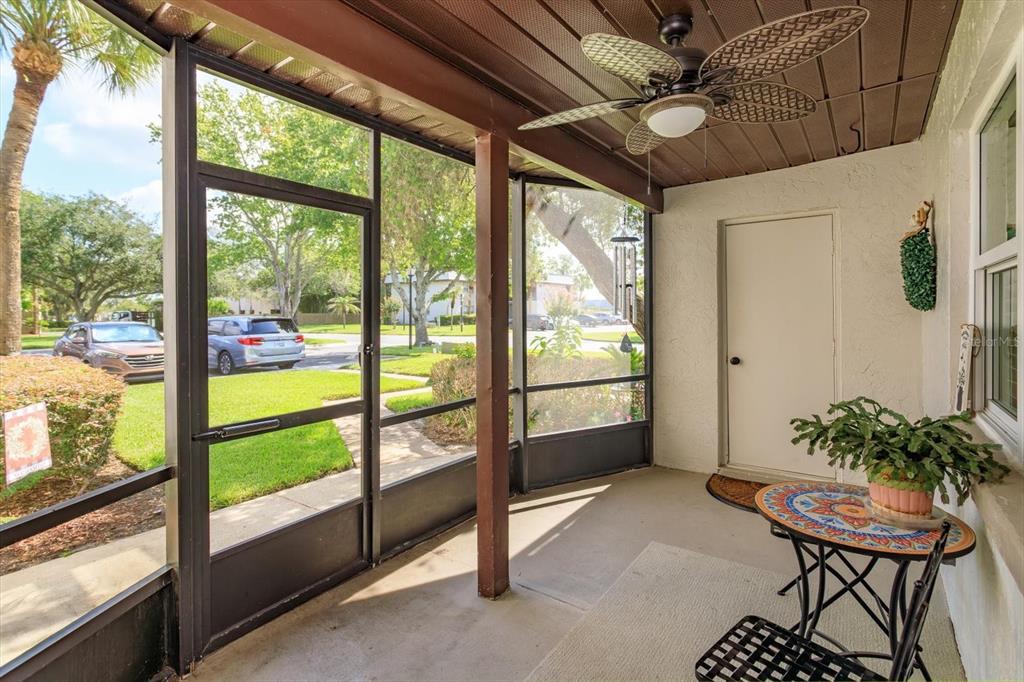 A screened-in porch features a ceiling fan, a small bistro table, and a white door — 27 WINDTREE LANE UNIT 102, WINTER GARDEN, FL