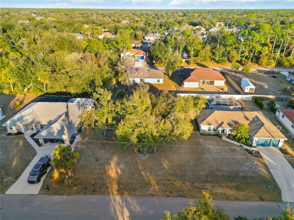 An aerial view shows two suburban houses with large front yards and surrounding wooded areas — Lot 26 HOLLAND STREET, NORTH PORT, FL