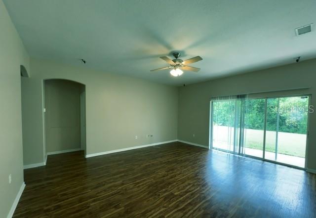 An empty living room features wood-look flooring, a ceiling fan, and sliding glass patio doors — 3161 WINDING TRAIL, KISSIMMEE, FL