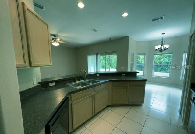 A kitchen features light wood cabinets, dark countertops, a double sink, and tile flooring — 3161 WINDING TRAIL, KISSIMMEE, FL