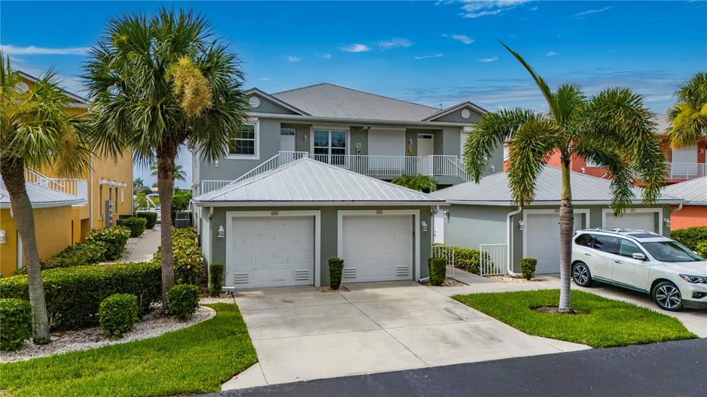 A two-story house with a metal roof, two garage doors, and palm trees in front — 2002 BAL HARBOR BOULEVARD UNIT 2221, PUNTA GORDA, FL