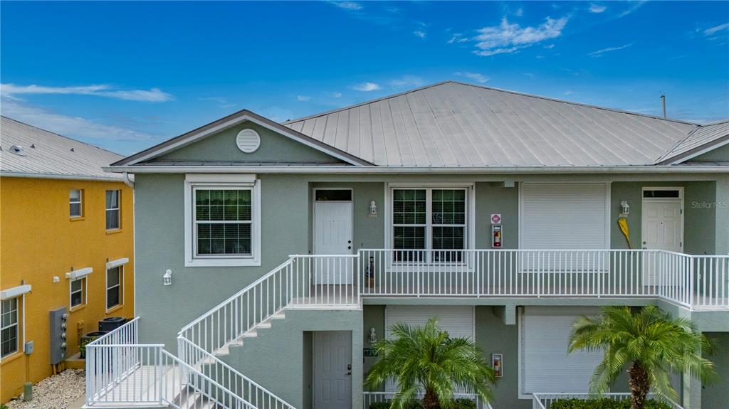 An exterior view of a two-story light green building with a metal roof and stairs — 2002 BAL HARBOR BOULEVARD UNIT 2221, PUNTA GORDA, FL