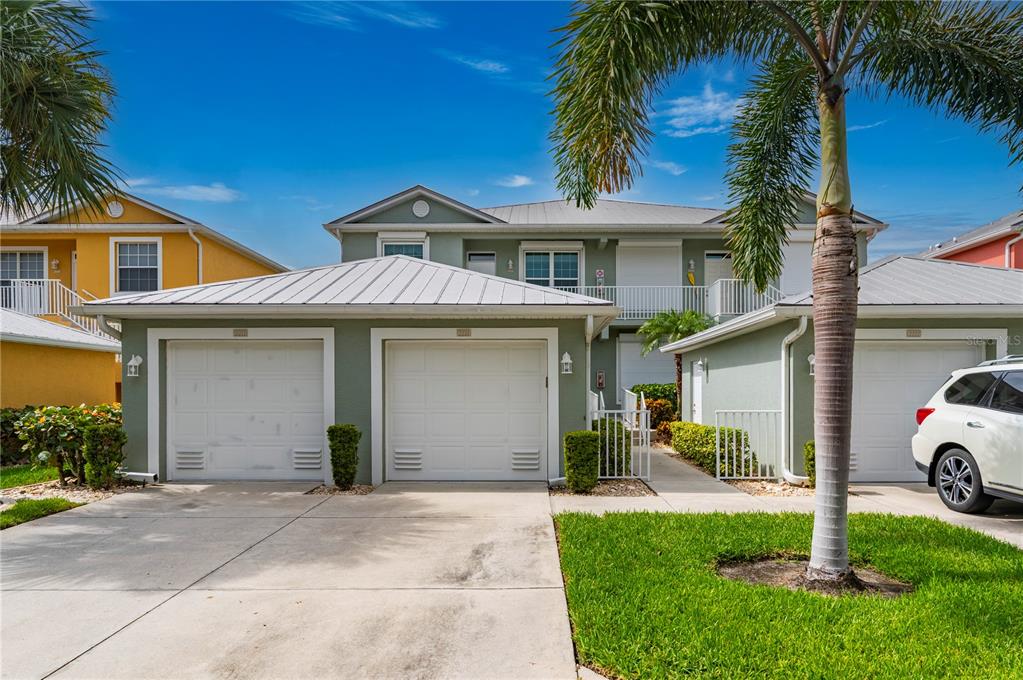 A two-story house with a light green exterior, metal roof, and three garage bays — 2002 BAL HARBOR BOULEVARD UNIT 2221, PUNTA GORDA, FL