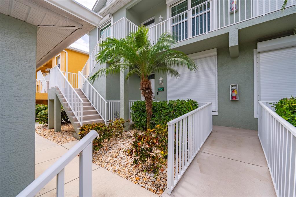 An exterior view of a multi-story building with a staircase, a palm tree, and landscaping — 2002 BAL HARBOR BOULEVARD UNIT 2221, PUNTA GORDA, FL
