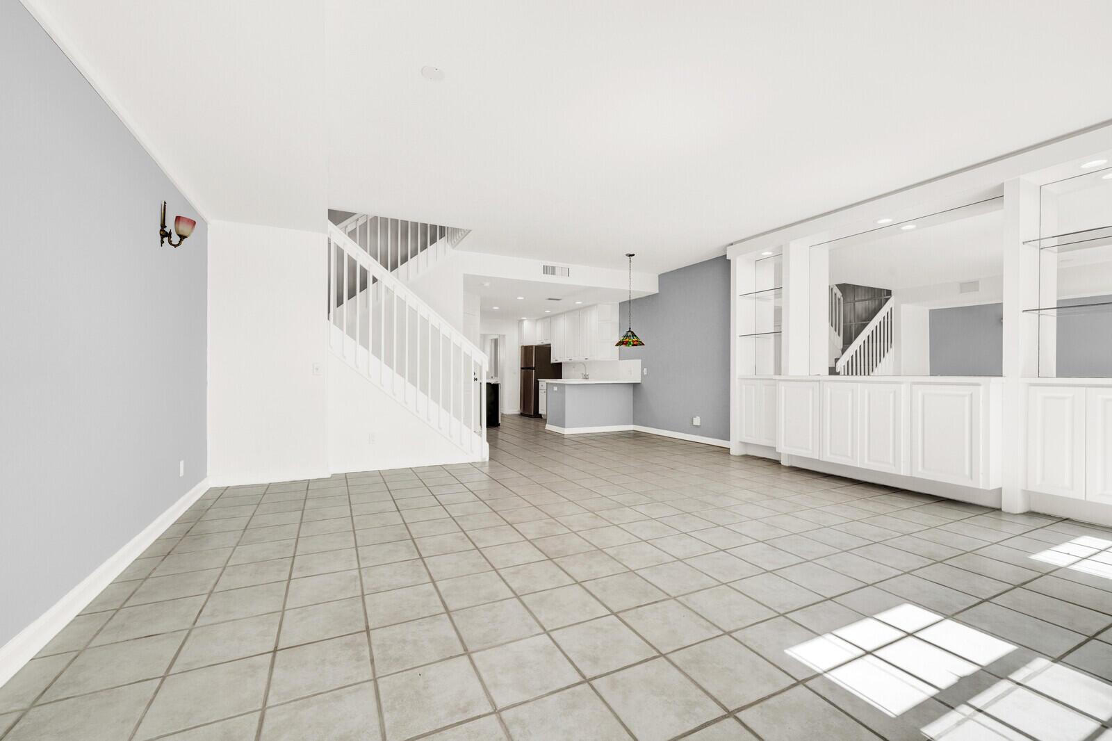 An open-concept living area features light gray walls, white built-in cabinetry, and tiled flooring — 133 Wentworth Court, Jupiter FL 33458, JUPITER, FL