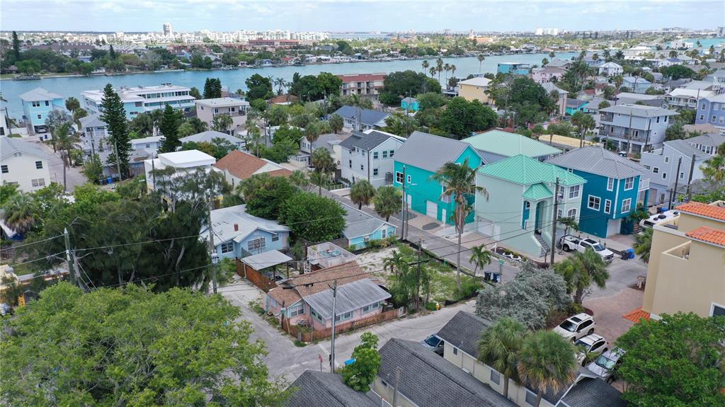 An aerial view shows a coastal neighborhood with colorful houses, palm trees, and a waterway — 101 95TH AVENUE, TREASURE ISLAND, FL