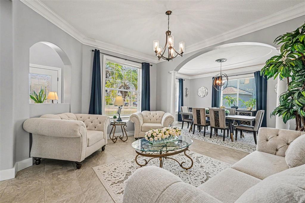 A living room and dining area feature light-colored furniture, tile flooring, and arched architectural details — 12915 CARLINGTON LN, RIVERVIEW, FL