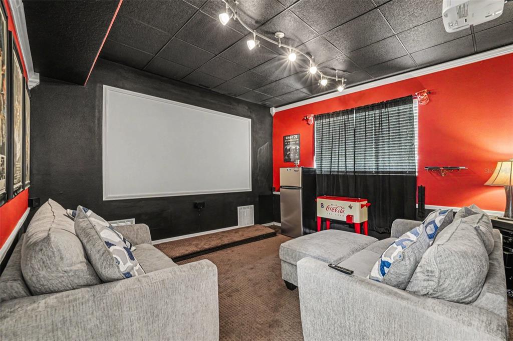 A home theater room features a projector screen, gray sofas, and a black ceiling — 12915 CARLINGTON LN, RIVERVIEW, FL