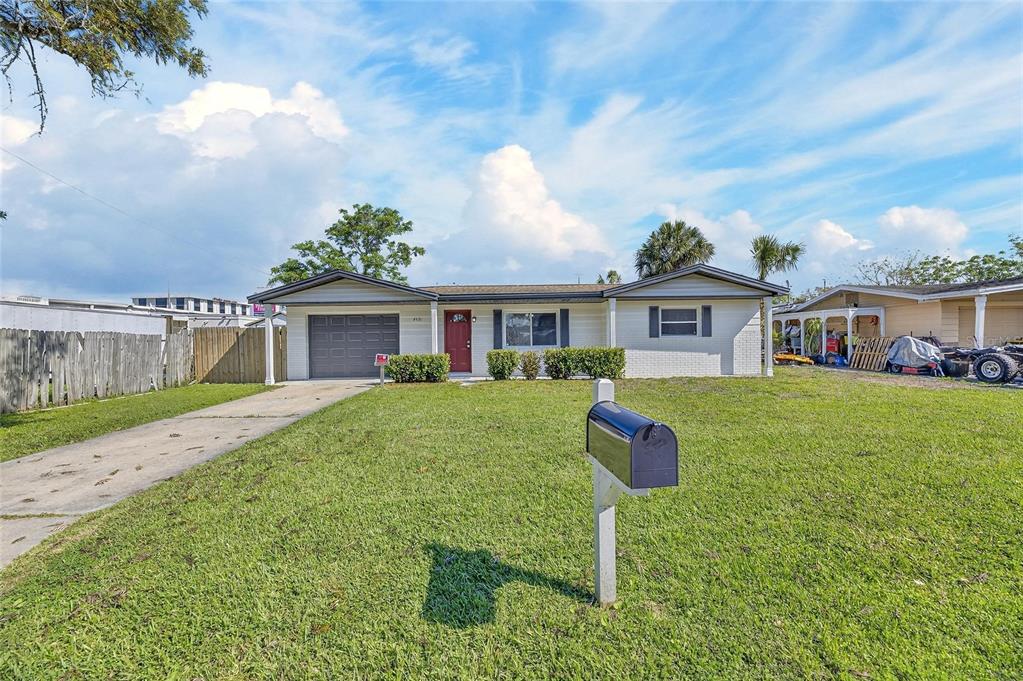 A single-story house with a gray garage, red front door, and a black mailbox — 4531 AEGEAN AVENUE, HOLIDAY, FL