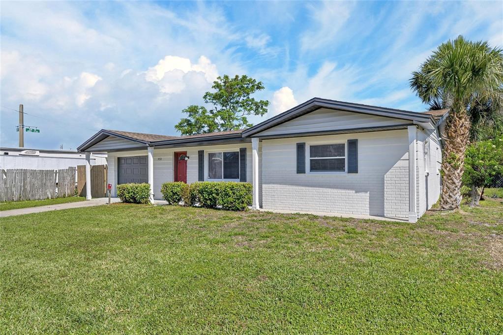 A single-story white brick house with a gray roof, front lawn, and a palm tree — 4531 AEGEAN AVENUE, HOLIDAY, FL