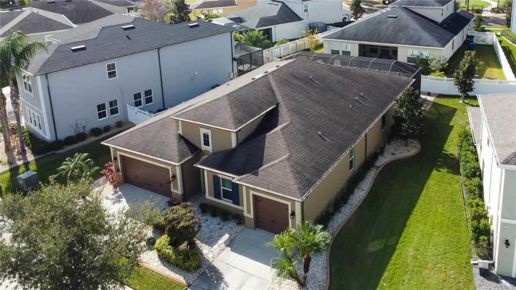 An aerial view shows a tan house with a dark shingled roof and two garages — 33423 AZALEA RIDGE DRIVE, WESLEY CHAPEL, FL