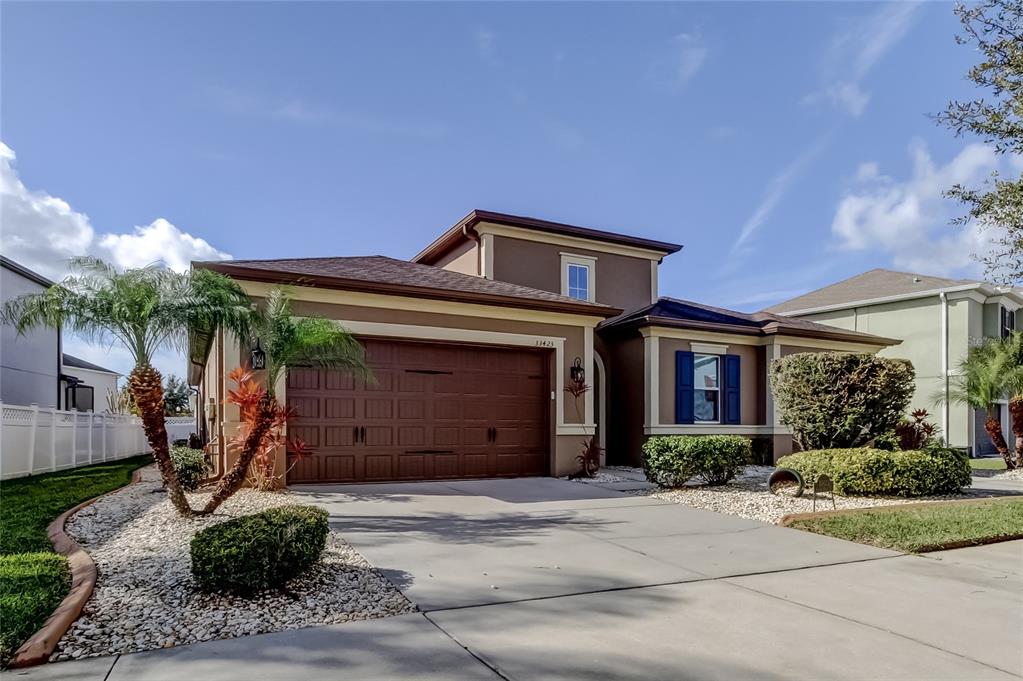 A two-story house with a brown garage, tan stucco walls, and a concrete driveway — 33423 AZALEA RIDGE DRIVE, WESLEY CHAPEL, FL