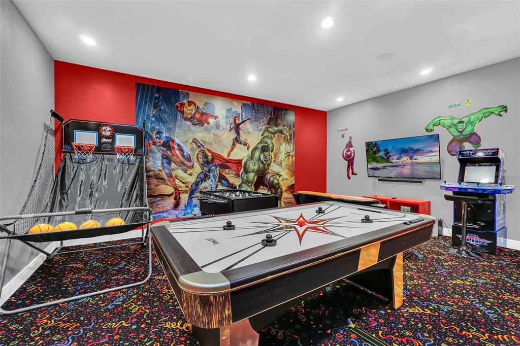 A game room features an air hockey table, arcade machine, basketball game, and Marvel-themed wall mural — 2630 DINVILLE STREET, KISSIMMEE, FL