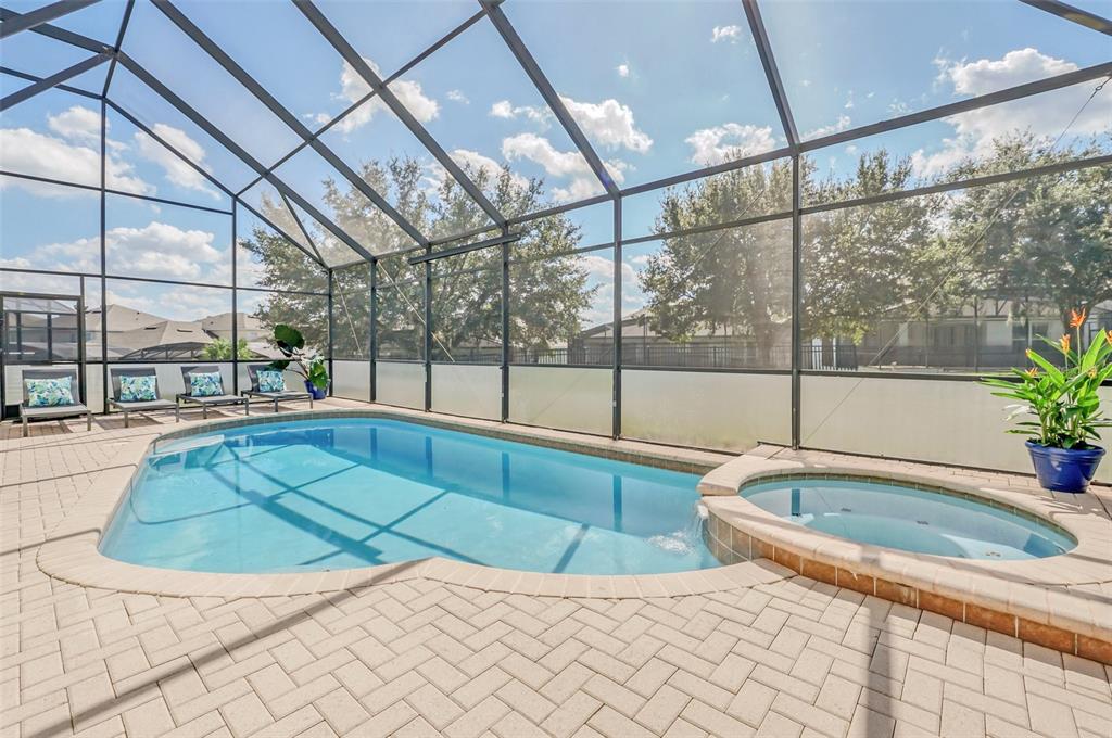 A screened-in patio features a swimming pool, a spillover spa, and brick paver decking — 2630 DINVILLE STREET, KISSIMMEE, FL
