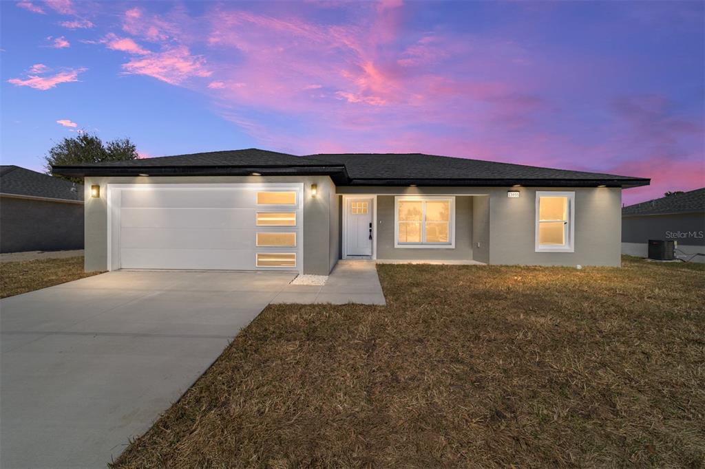 A single-story house with a gray exterior, a two-car garage, and a concrete driveway — 14767 SW 22 PLACE, OCALA, FL