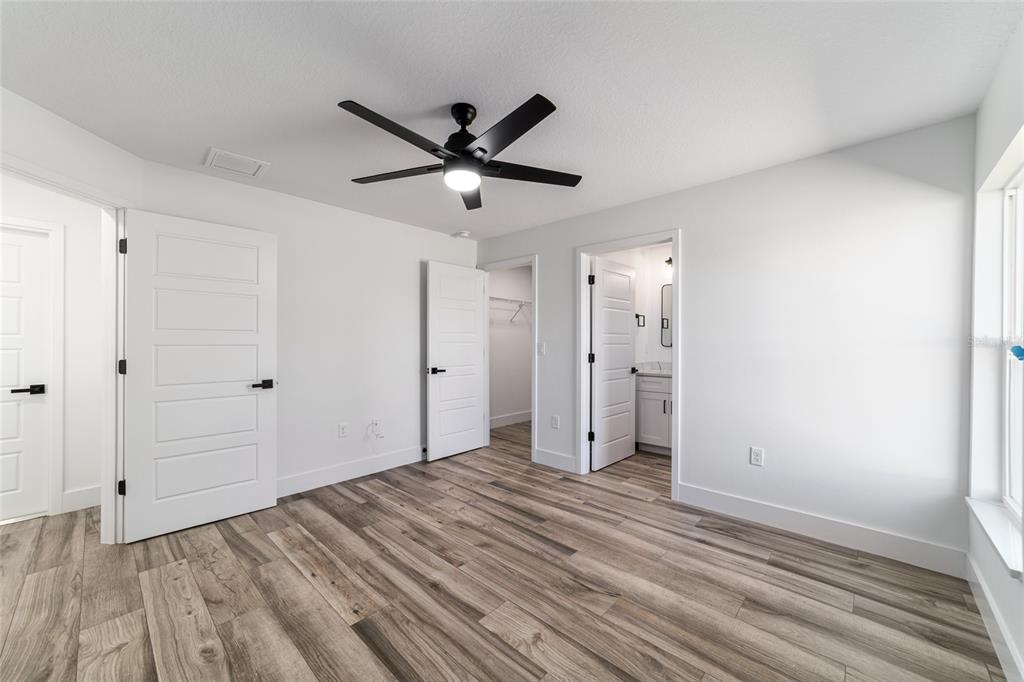 A bedroom with white walls, wood-look flooring, a ceiling fan, and two interior doors — 14767 SW 22 PLACE, OCALA, FL