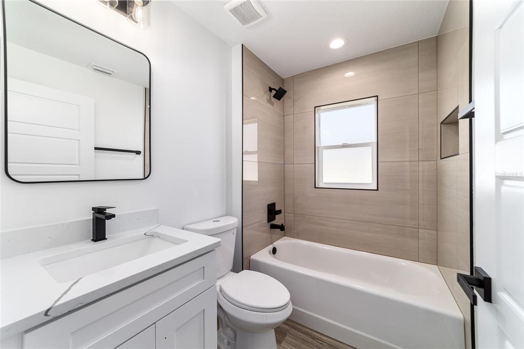 A modern bathroom features a white vanity, a toilet, and a bathtub with tiled walls — 14767 SW 22 PLACE, OCALA, FL