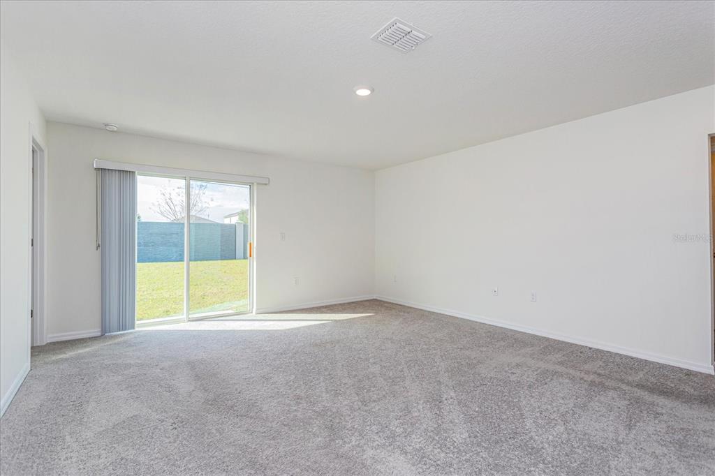 An empty room with gray carpet, white walls, and a sliding glass door to a yard — 352 TOWNS CIRCLE, HAINES CITY, FL