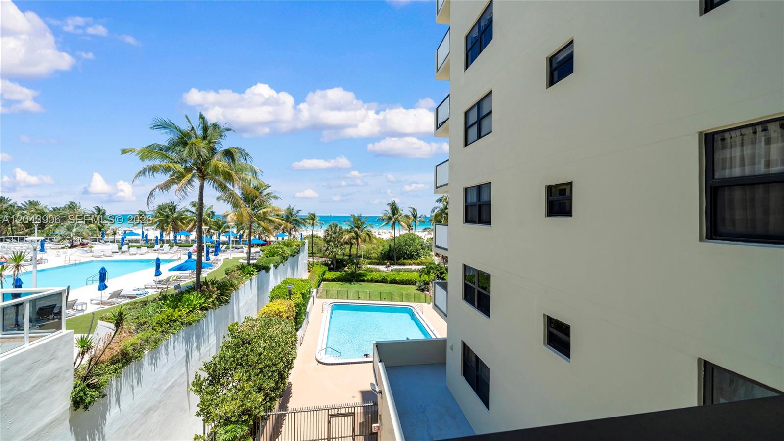 An elevated view shows a building exterior, two swimming pools, palm trees, and the ocean — 1623 Collins Ave # 415, Miami Beach FL 33139, MIAMI BEACH, FL