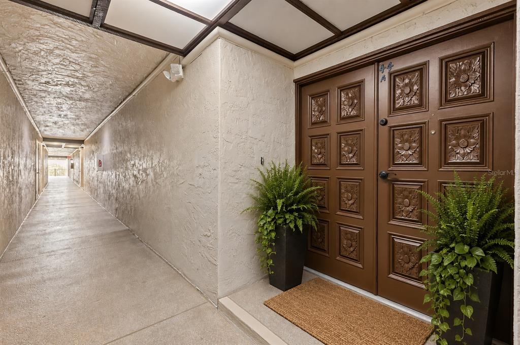 A brown double door with floral panels sits at the end of a concrete hallway — 3021 COUNTRYSIDE BOULEVARD UNIT 44A, CLEARWATER, FL