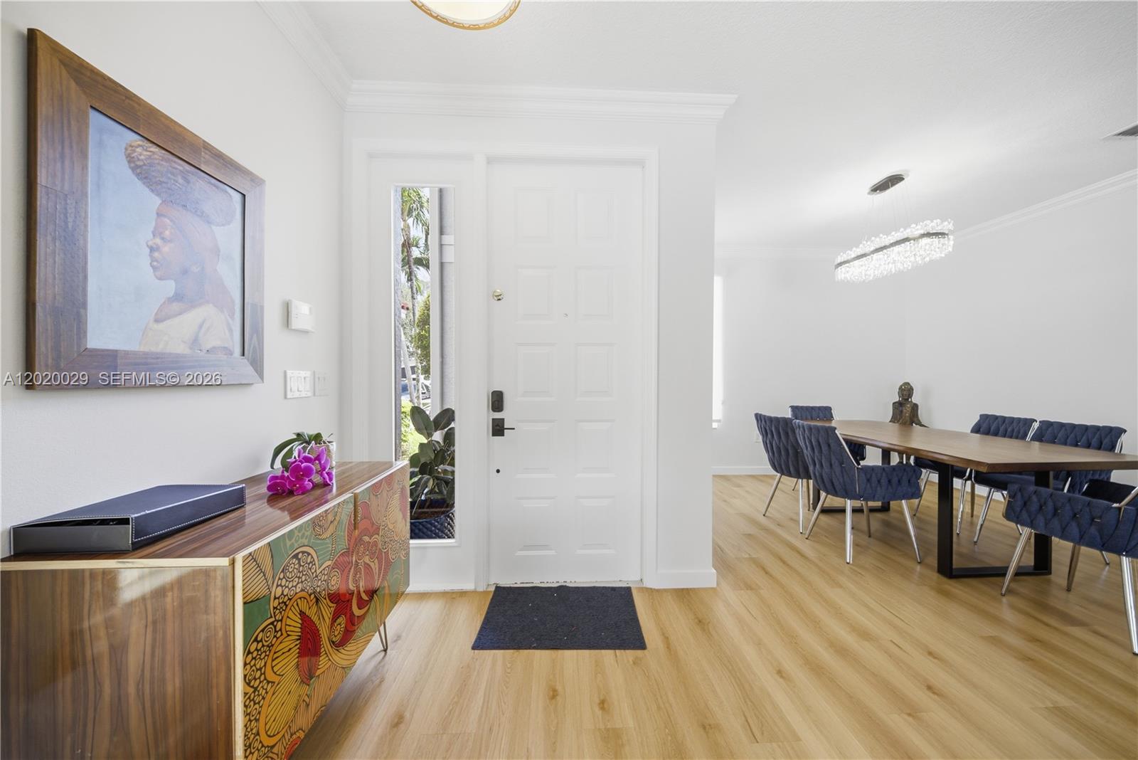 An entryway with a patterned console table leads into a dining room with blue chairs — 9985 Marsala Way, Delray Beach FL 33446, DELRAY BEACH, FL