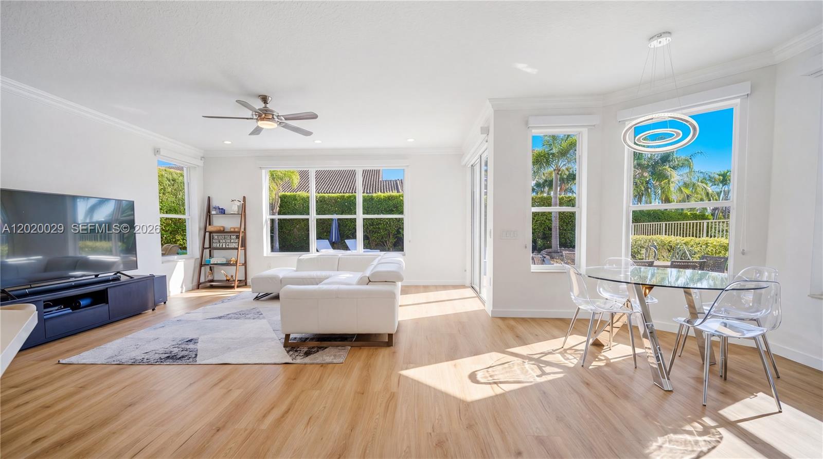 A bright living and dining area features white walls, light wood flooring, and large windows — 9985 Marsala Way, Delray Beach FL 33446, DELRAY BEACH, FL