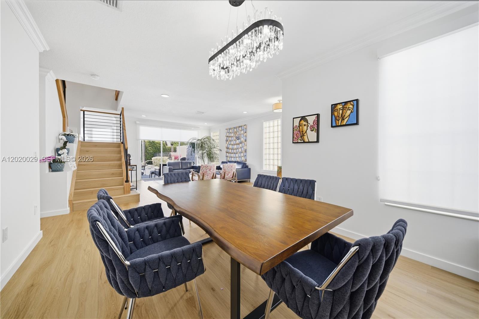 A dining room features a wooden table, blue chairs, and a modern crystal chandelier — 9985 Marsala Way, Delray Beach FL 33446, DELRAY BEACH, FL