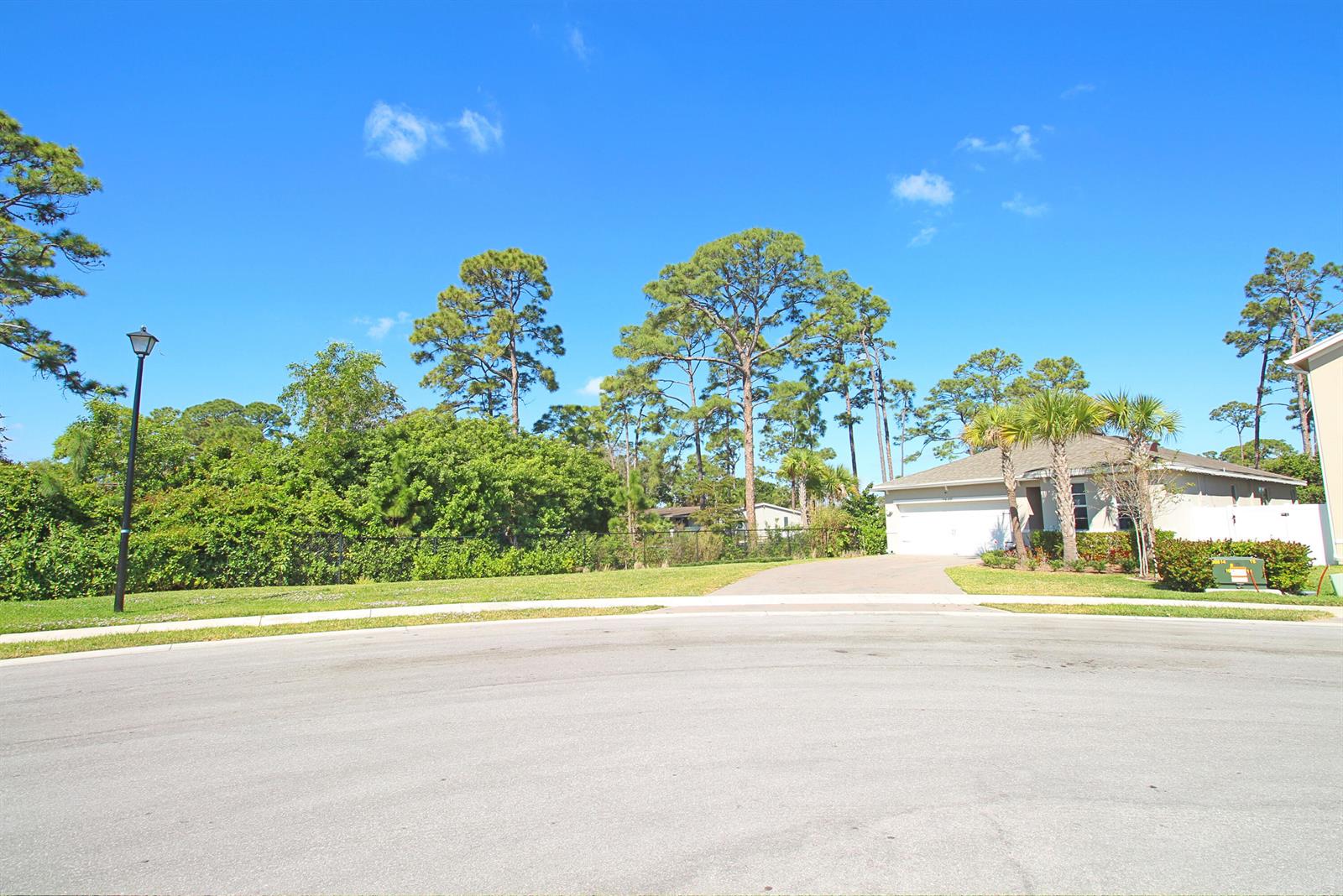 A suburban street view shows a house with a driveway, palm trees, and lush landscaping — 2549 Timber Forest Drive, West Palm Beach FL 33415, WEST PALM BEACH, FL
