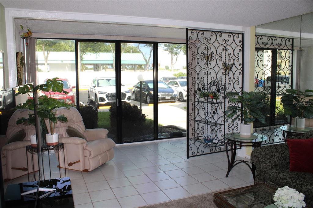 A living room features tile flooring, a decorative metal room divider, and large sliding glass doors — 14130 ROSEMARY LANE UNIT 1117, LARGO, FL