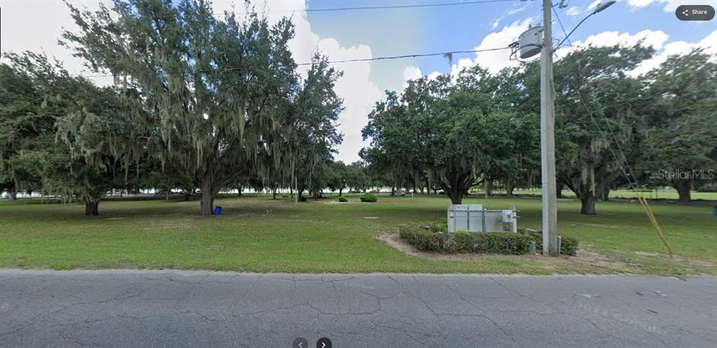 A grassy vacant lot features several large oak trees and a utility box near the road — N/A, LAKE WALES, FL
