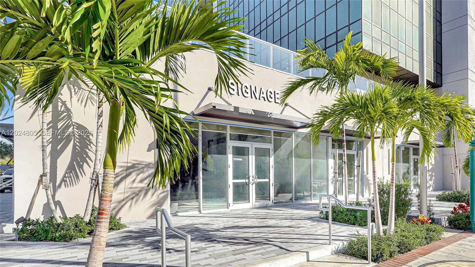 A ground-level commercial storefront entrance features glass doors, a beige facade, and palm trees — 1909 Tyler St, Hollywood FL 33020, HOLLYWOOD, FL
