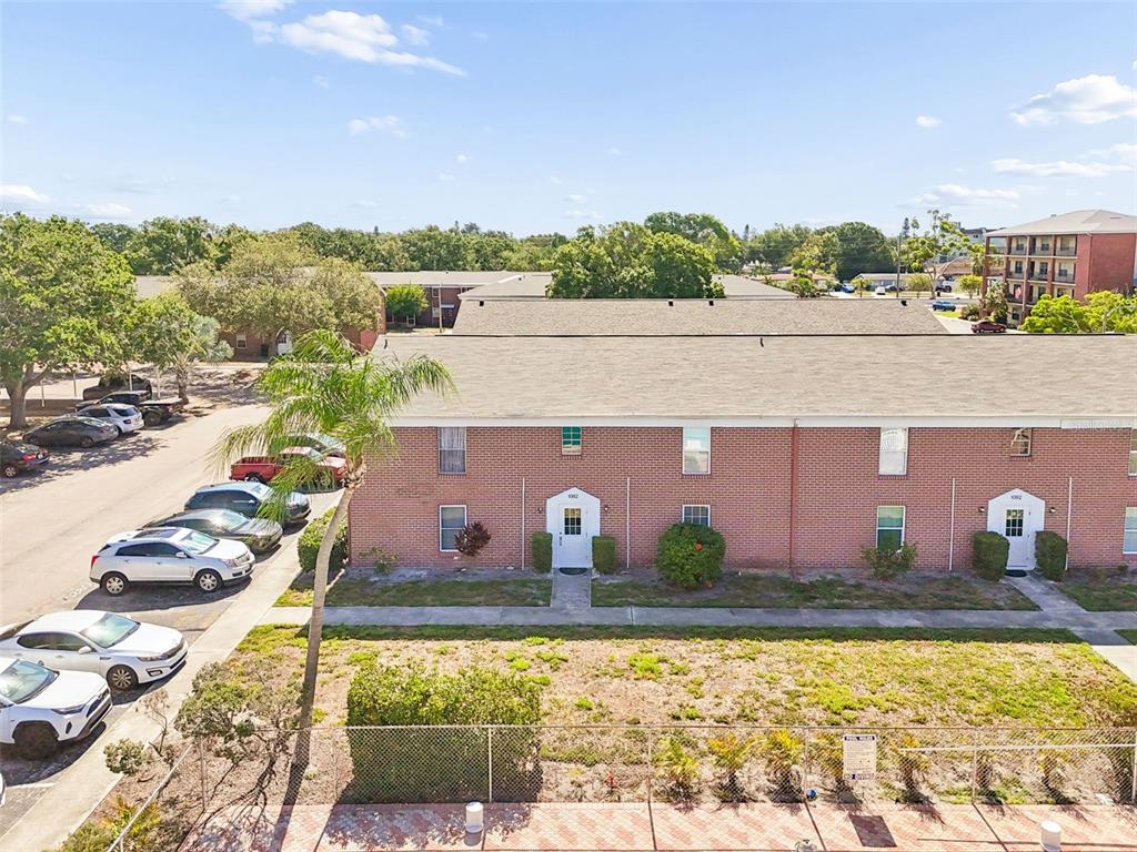 An aerial view shows a brick apartment building with a parking lot and a pool — 1062 85TH TERRACE N UNIT A, ST PETERSBURG, FL