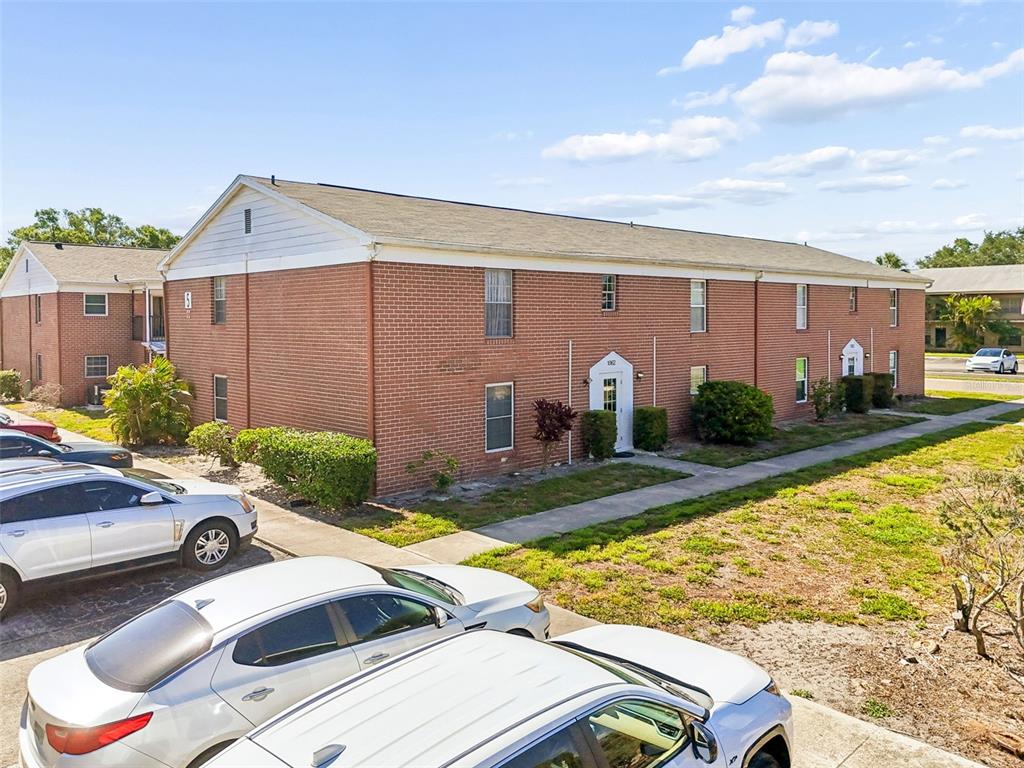 A two-story brick apartment building features a white arched entryway and a paved parking lot — 1062 85TH TERRACE N UNIT A, ST PETERSBURG, FL